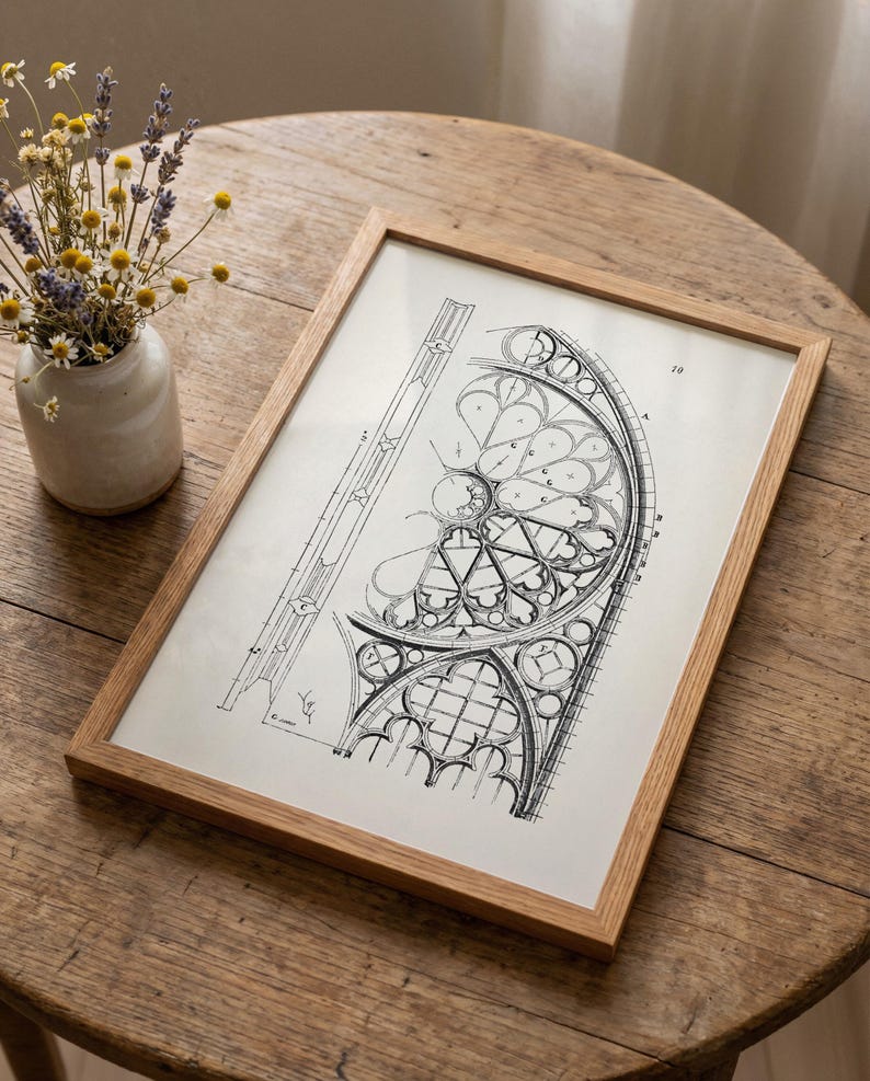 Puede incluir: Un dibujo arquitect&oacute;nico en blanco y negro enmarcado de un dise&ntilde;o de vidriera. El dibujo est&aacute; en un marco de madera marr&oacute;n claro. Un peque&ntilde;o jarr&oacute;n con flores secas se encuentra a la izquierda del marco sobre una mesa de madera.