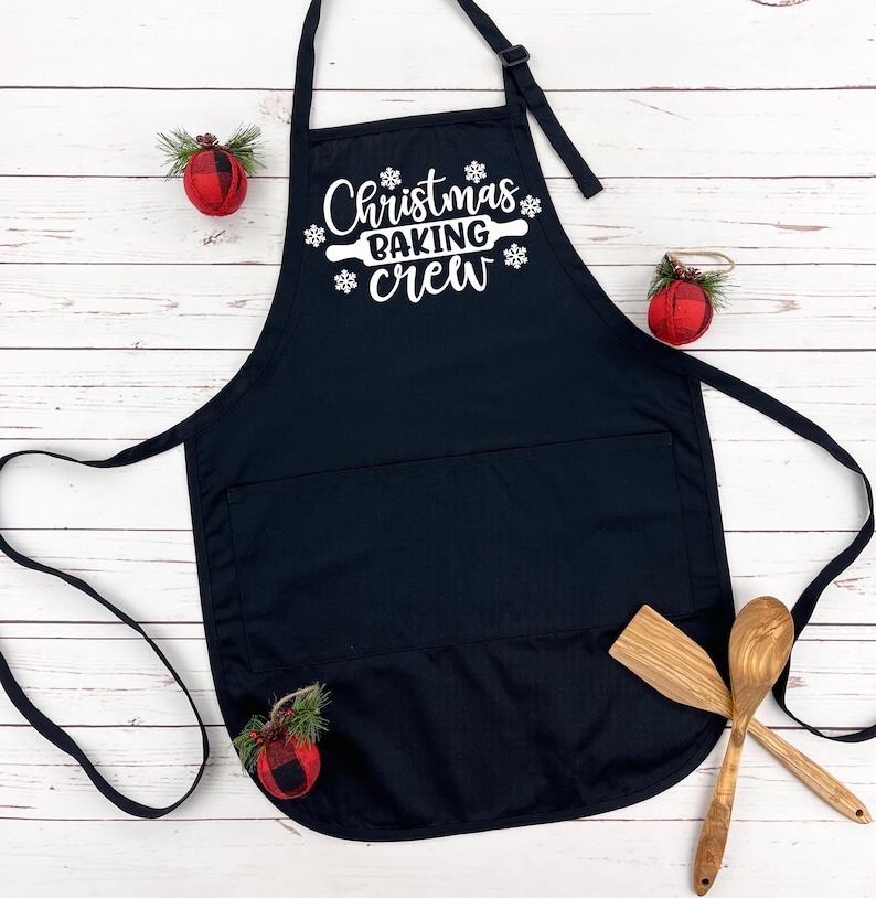 May include: Black Christmas baking apron with a white design that says "Christmas Baking Crew" with a rolling pin and snowflakes.