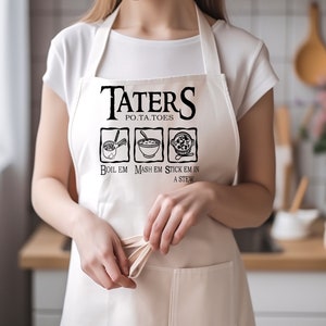 May include: White kitchen apron with the text "Taters" and "Po.Ta.Toes" in black. The apron has three black and white illustrations of cooking methods for potatoes: "Boil Em", "Mash Em", and "Stick Em In A Stew".