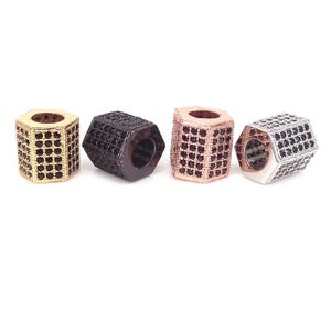 Puede incluir: Cuatro cuentas hexagonales en oro, negro, oro rosa y plata. Cada cuenta está cubierta de pequeñas piedras cuadradas. Las cuentas tienen un centro hueco y se muestran sobre un fondo blanco. Estas cuentas son adecuadas para la fabricación de joyas.
