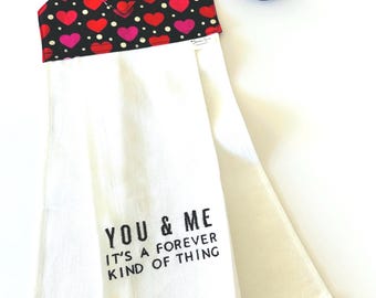 May include: White kitchen towel with red heart trim and a black and white heart print hanging loop. The towel has the text "You & Me It's a forever kind of thing" embroidered on it.