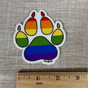 May include: A rainbow paw print sticker with the text "FinBazi." The sticker is approximately 1 inch in diameter.