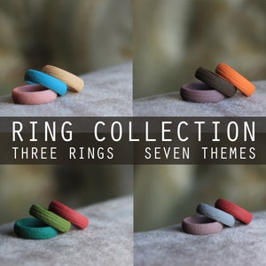 May include: A collection of three silicone rings in different colors. The rings are stacked on top of each other. The text "RING COLLECTION" is displayed above the rings, and the text "THREE RINGS SEVEN THEMES" is displayed below the rings.