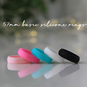 May include: Five silicone rings in pink, blue, turquoise, white and black. The rings are 5.7mm wide and are stacked on top of each other.
