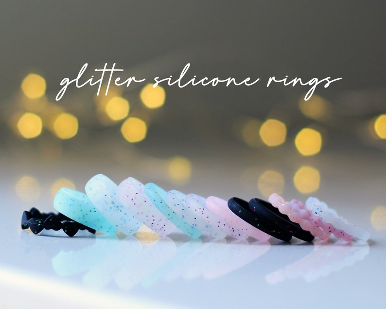 Pode incluir: Uma fila de an&eacute;is de silicone com glitter embutido. Os an&eacute;is s&atilde;o de v&aacute;rias cores, incluindo preto, branco, rosa e azul.