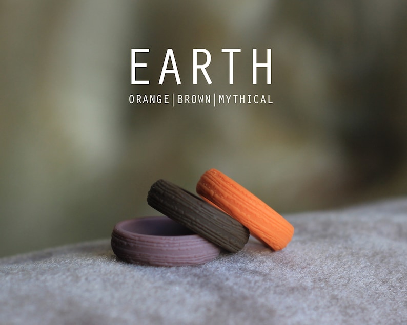 May include: Three stacked silicone rings in orange, brown, and purple. The rings have a textured surface and are labeled "EARTH | ORANGE | BROWN | MYTHICAL".