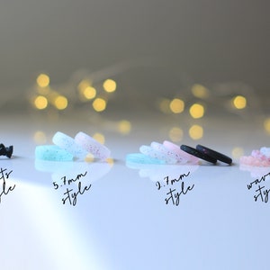 Pode incluir: Quatro an&eacute;is de silicone em diferentes estilos. O primeiro anel &eacute; preto com um design de cora&ccedil;&atilde;o. O segundo anel &eacute; azul claro com glitter. O terceiro anel &eacute; preto com glitter. O quarto anel &eacute; rosa com glitter. Os an&eacute;is s&atilde;o etiquetados como "hearts style", "5,7 mm style", "2,7 mm style" e "wavy style".