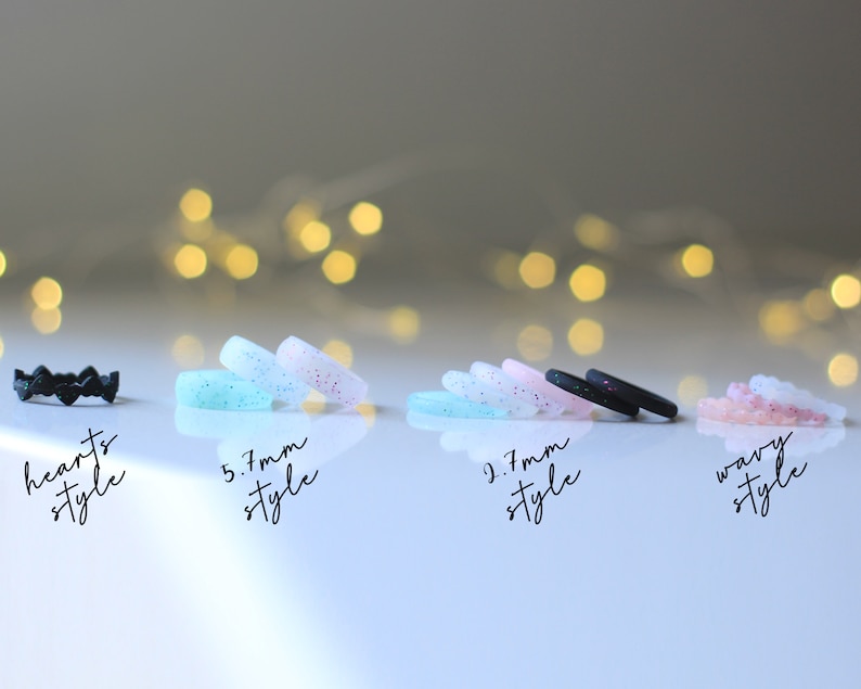 Pode incluir: Quatro an&eacute;is de silicone em diferentes estilos. O primeiro anel &eacute; preto com um design de cora&ccedil;&atilde;o. O segundo anel &eacute; azul claro com glitter. O terceiro anel &eacute; preto com glitter. O quarto anel &eacute; rosa com glitter. Os an&eacute;is s&atilde;o etiquetados como "hearts style", "5,7 mm style", "2,7 mm style" e "wavy style".