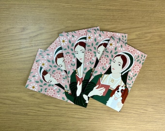 May include: Five pink cards with a floral pattern and a portrait of a woman in a green dress and a white head covering. The woman is holding a book and a dog is sitting next to her. The dog is brown and white with long ears.