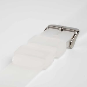 Puede incluir: Primer plano de una correa de reloj blanca con una hebilla plateada. La correa está hecha de un material translúcido y tiene una serie de bucles rectangulares. La hebilla es de diseño clásico, con un acabado pulido.