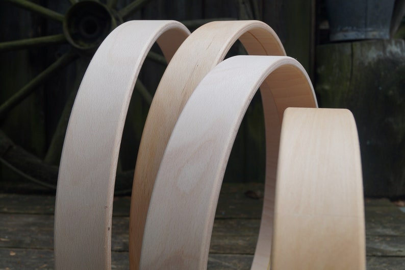 May include: Three unfinished wooden hoops of varying sizes, stacked on top of each other. The hoops are made of light-colored wood and have a smooth, polished finish.