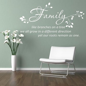Puede incluir: Una silla blanca moderna y un jarrón blanco con calas se encuentran frente a una pared verde apagada. La pared presenta la palabra "Family" en escritura con la cita "como ramas en un árbol, todos crecemos en una dirección diferente, pero nuestras raíces permanecen como una."