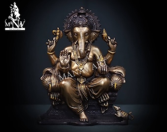 Könnte beinhalten: Eine bronzefarbene Statue des hinduistischen Gottes Ganesha, sitzend auf einem Thron. Die Statue weist aufwendige Details auf, darunter eine Krone, Schmuck und eine Ratte am Sockel. Der Hintergrund ist dunkel.