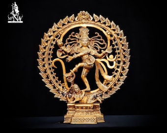 May include: A gold-colored metal statue of the Hindu deity Shiva in the Nataraja pose, dancing on a demon. The statue is surrounded by a circular halo with intricate details. The statue is on a pedestal with ornate carvings.
