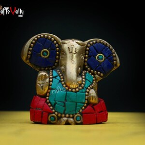 Puede incluir: Una peque&ntilde;a estatua dorada de Ganesha, el dios hind&uacute; de los comienzos, la sabidur&iacute;a y la prosperidad. La estatua est&aacute; decorada con mosaicos azules, verdes y rojos.