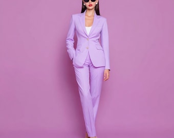May include: A light purple business suit, including a blazer and trousers, is worn with a white top and sunglasses. The suit has a tailored fit and is paired with matching high-heeled shoes. The background is a solid purple.