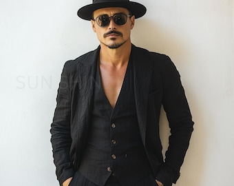 May include: A man wearing a black suit with a vest, a black fedora hat, and sunglasses. He is standing in front of a white wall.