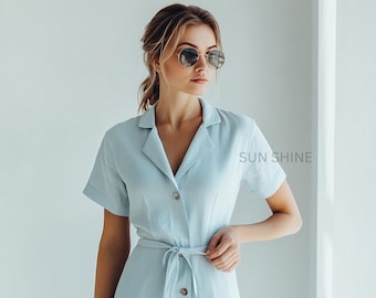 May include: A light blue dress with short sleeves and a tie waist. The dress has a button-down front and a collar. The text "SUN SHINE" is visible on the right side of the image. The person in the image is wearing round sunglasses.