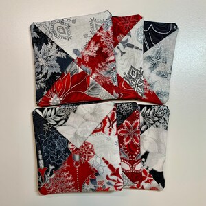 May include: Set of four red, white, and gray fabric coasters with a geometric pattern. The coasters are made of patchwork fabric and have a quilted design.
