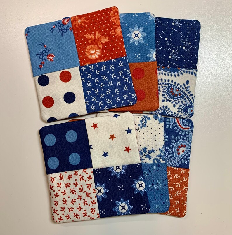 May include: Set of six fabric coasters with a patchwork design. Each coaster features a different combination of blue, red, and white patterns.