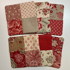 May include: Set of six red and beige fabric coasters with a patchwork design. Each coaster is made of four squares of different patterned fabric.