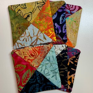 May include: A set of six colorful fabric coasters with a patchwork design featuring various floral patterns. The coasters are made of a soft, textured fabric and are perfect for protecting surfaces from heat and spills.