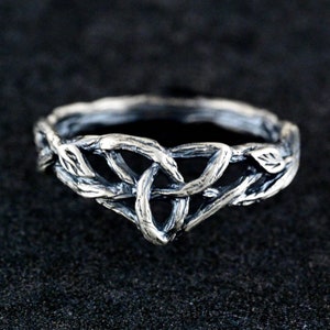 May include: A silver ring featuring a design of interwoven branches and leaves.