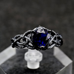 May include: A silver ring featuring a dark blue heart-shaped gemstone set within a twisted vine design.
