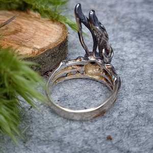 K&ouml;nnte beinhalten: Ein silberner Ring mit einem detaillierten Design eines Astes mit Bl&auml;ttern. Der Ring wird von der Seite gezeigt, wobei die Band zum Betrachter zeigt.