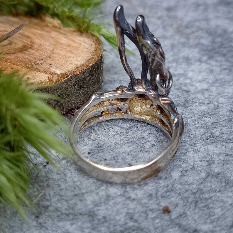K&ouml;nnte beinhalten: Ein silberner Ring mit einem detaillierten Design eines Astes mit Bl&auml;ttern. Der Ring wird von der Seite gezeigt, wobei die Band zum Betrachter zeigt.