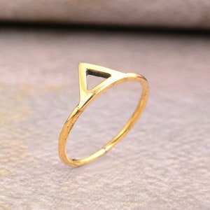 May include: A gold-toned ring with a triangle design. The triangle is open and the ring is thin.