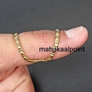 May include: A gold thumb ring with a textured design. The ring is worn on the thumb of a person's hand.