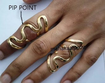 Pode incluir: Duas alianças de ouro com um design ondulado. As alianças são usadas no dedo indicador e no dedo médio. O texto "PIP POINT" está escrito na imagem.