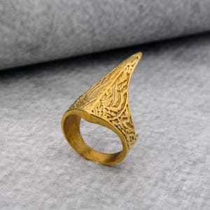 Könnte beinhalten: Ein goldfarbener Ring mit einem komplizierten, strukturierten Design. Der Ring ist oben spitz und hat ein breites Band.
