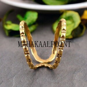 May include: A gold ring with a textured design. The ring is made of two bands that are connected at the top.