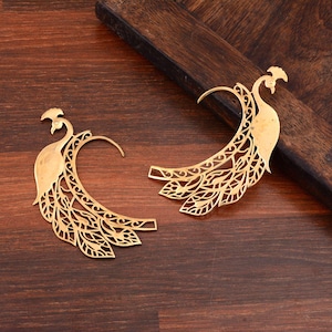 Könnte beinhalten: Ein Paar goldfarbene Ohrringe in Form eines Pfaus. Die Ohrringe sind aus Metall und haben ein filigranes, kunstvolles Design. Die Ohrringe sind perfekt, um jedem Outfit einen Hauch von Eleganz zu verleihen.