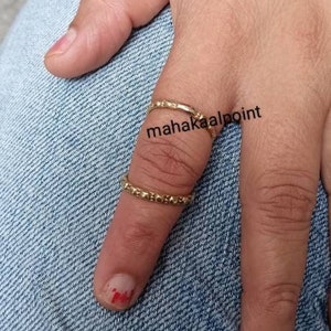May include: Two gold rings on a finger. The rings are thin and have a textured surface. The text "mahakaalpoint" is visible on the finger.