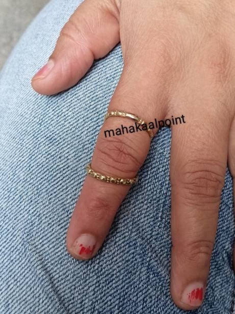 May include: Two gold rings on a finger. The rings are thin and have a textured surface. The text "mahakaalpoint" is visible on the finger.