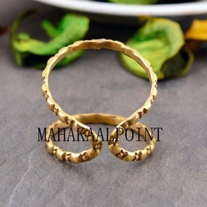 May include: Gold-toned double ring with a textured design. The ring is open on one side and has a curved shape.