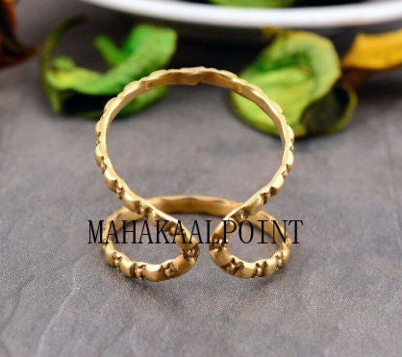 May include: Gold-toned double ring with a textured design. The ring is open on one side and has a curved shape.