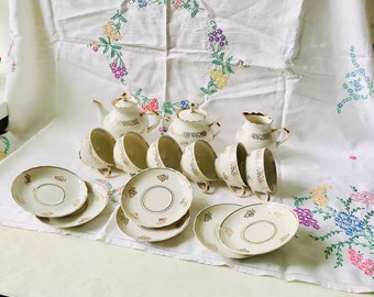 May include: A vintage tea set with a white teapot, creamer, and six cups and saucers. The set features a delicate floral pattern and gold trim.