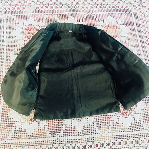 Op de afbeelding: Een zwart, mouwloos vest met een satijnachtige afwerking. Het vest heeft een eenvoudig ontwerp met een ronde hals en geen sluitingen.