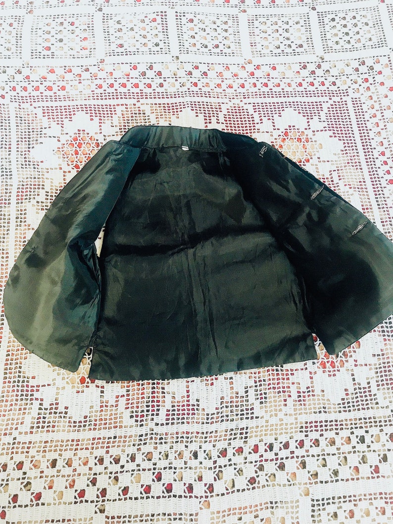 Op de afbeelding: Een zwart, mouwloos vest met een satijnachtige afwerking. Het vest heeft een eenvoudig ontwerp met een ronde hals en geen sluitingen.