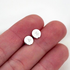 May include: A pair of silver initial earrings with the letters A and E.