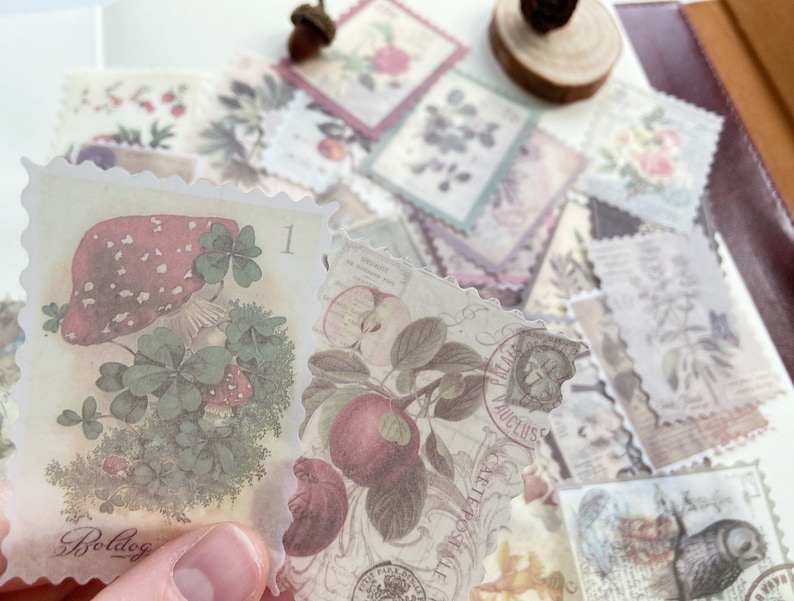 May include: A collection of vintage-style paper stamps with botanical and nature-themed illustrations. The stamps feature images of mushrooms, apples, flowers, and other natural elements in soft, muted colors. The stamps have a scalloped edge and are slightly translucent.