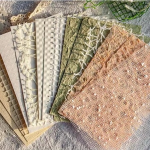 May include: A collection of textured paper sheets in various colors, including beige, cream, and green. The papers have different patterns, such as lattice, grid, and floral designs. The papers are arranged in a fan shape, showcasing their unique textures.