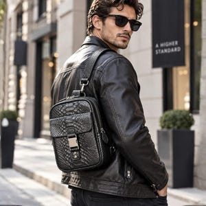 Man wearing black python snakeskin sling backpack with leather jacket in luxury city setting