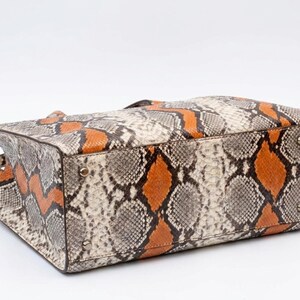 Bottom view of orange exotic python leather tote bag with metal feet