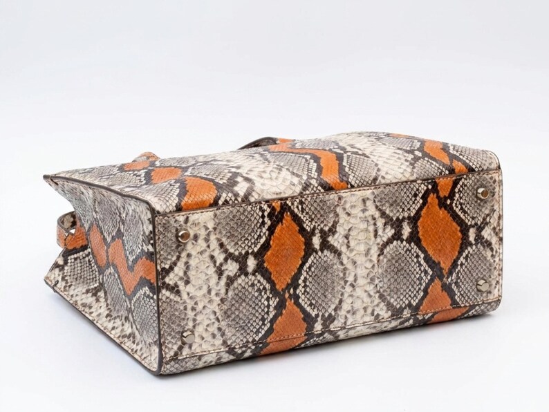 Bottom view of orange exotic python leather tote bag with metal feet