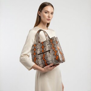 Elegant woman holding orange python snakeskin luxury tote bag